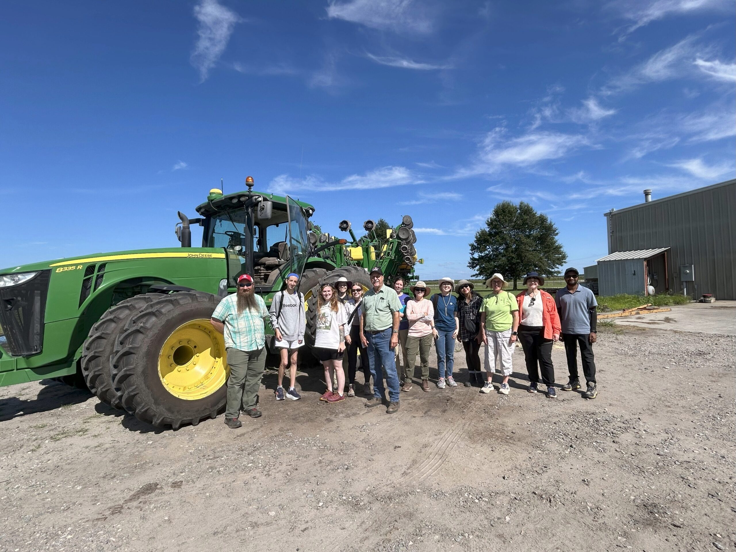 Students with a farmer in front of a tractor.