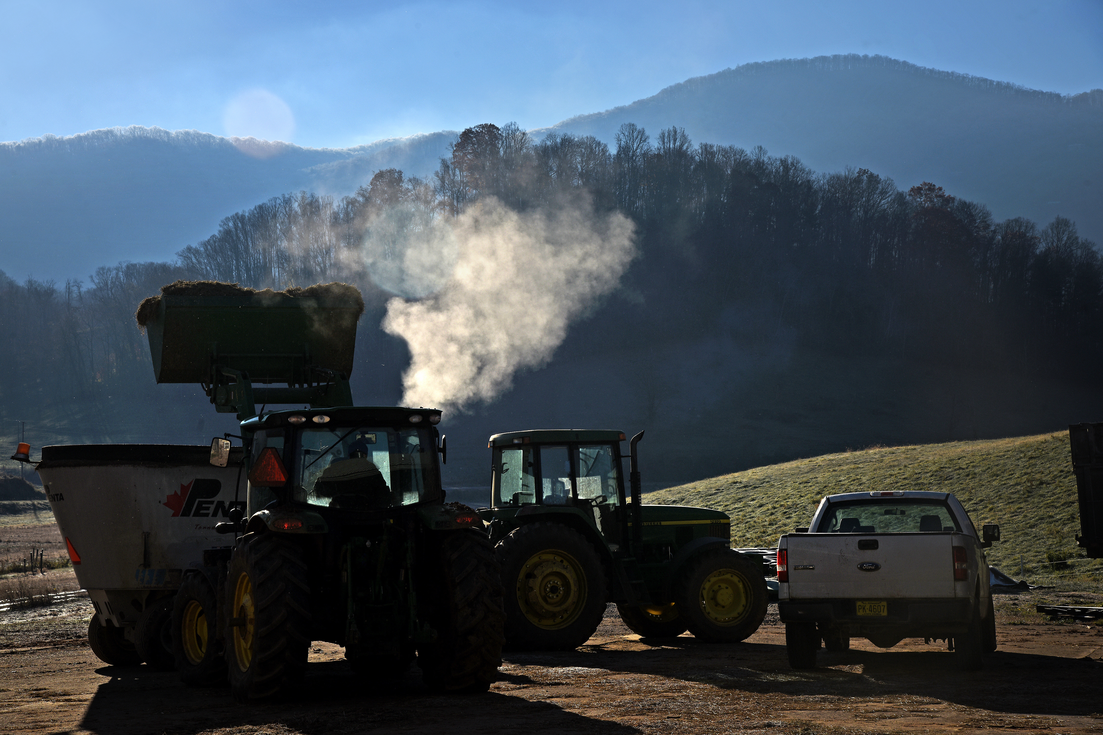 Wooded hills with trucks and tractors in the foreground